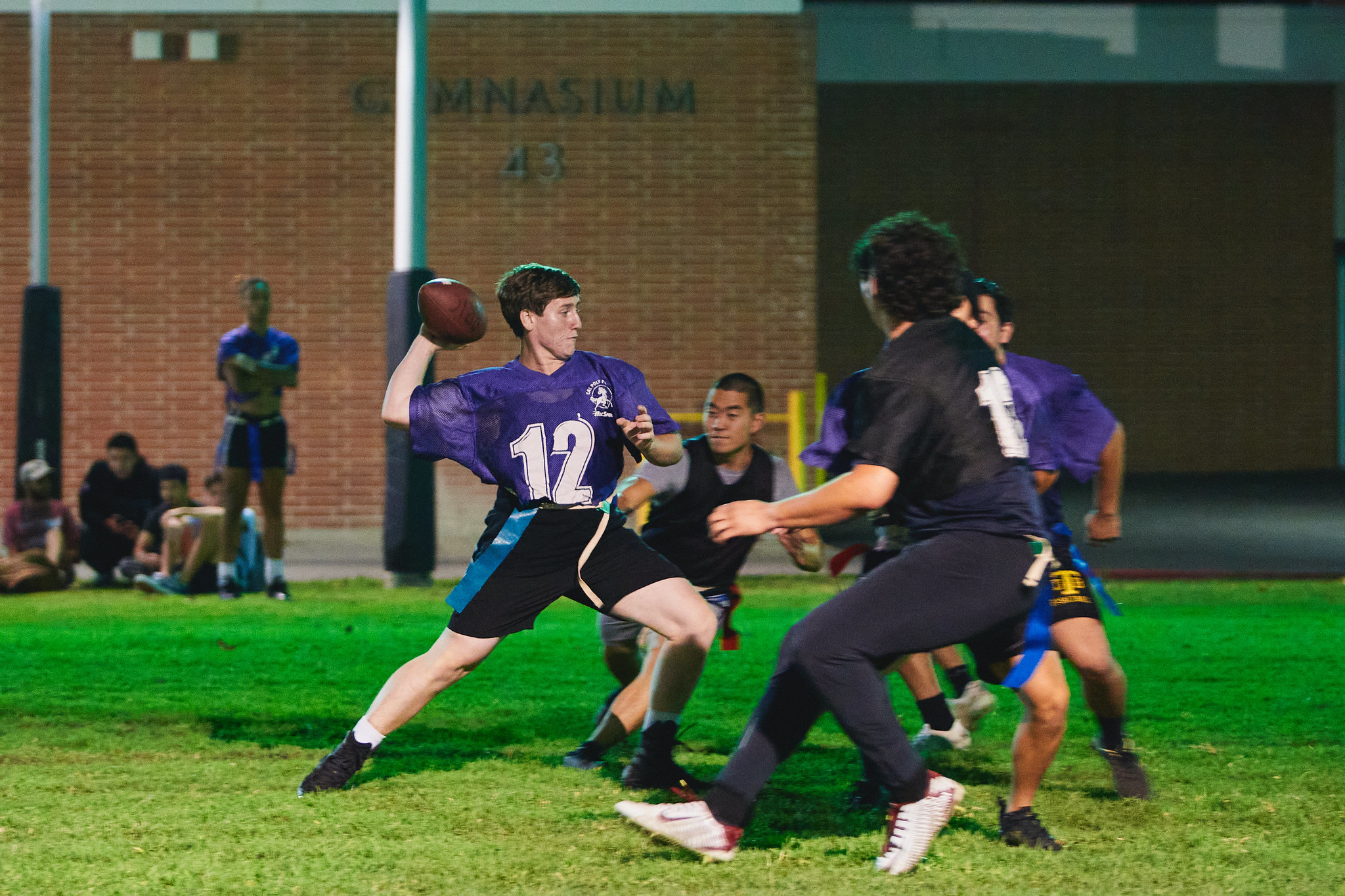 One student throwing a football and others attempting to grab his flag in a game of football.