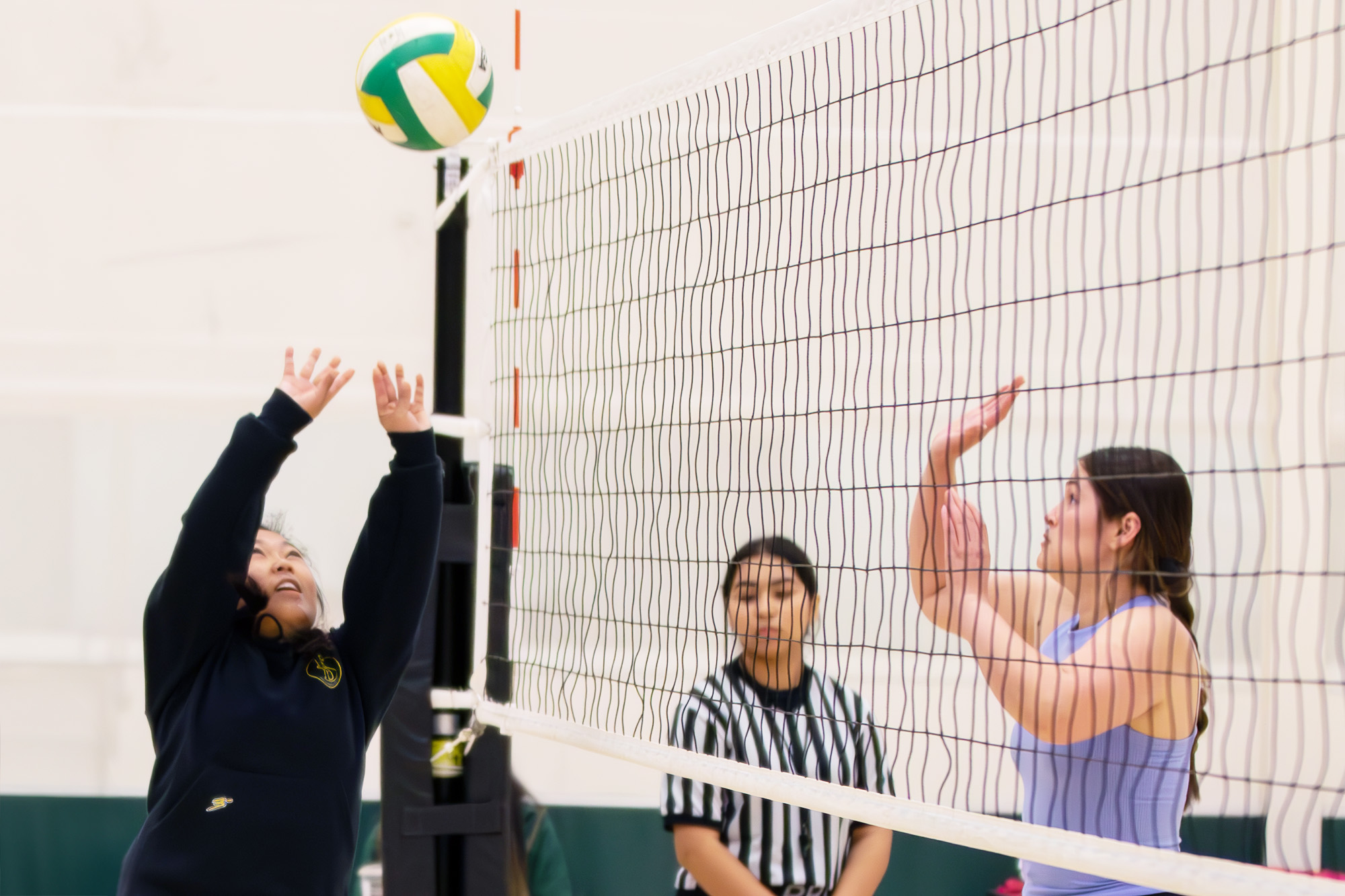 students hitting a volleyball over a net