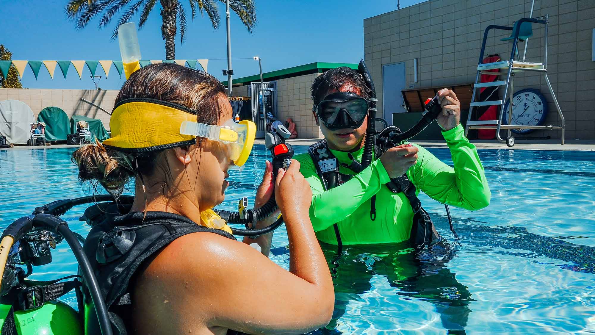 scuba diving instructor teaching a student how to use scuba gear in a swimming pool