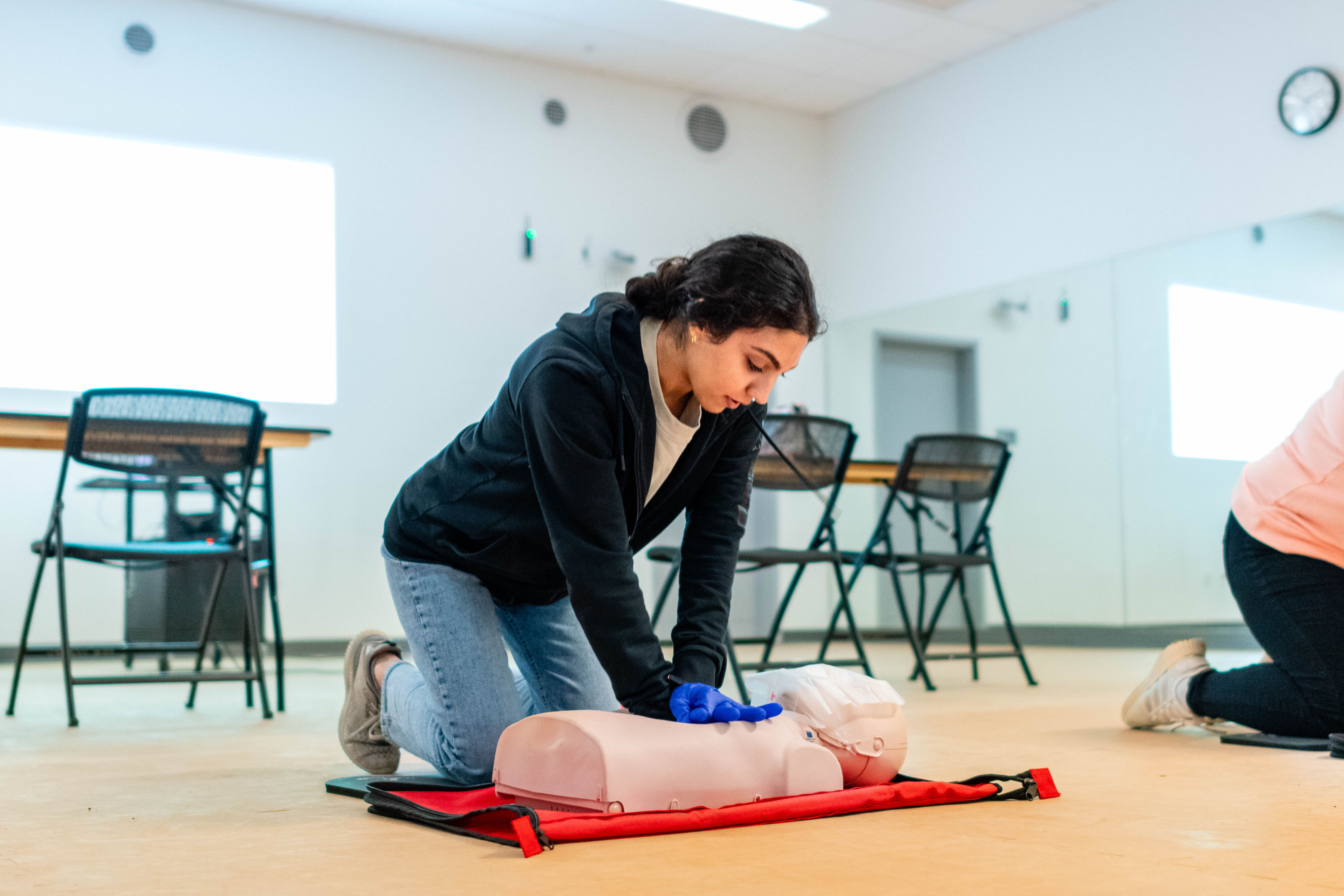 A person is practicing CPR on a mannequin in a training room