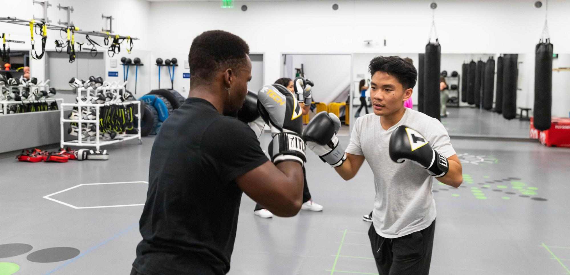 Two students sparing with boxing gloves