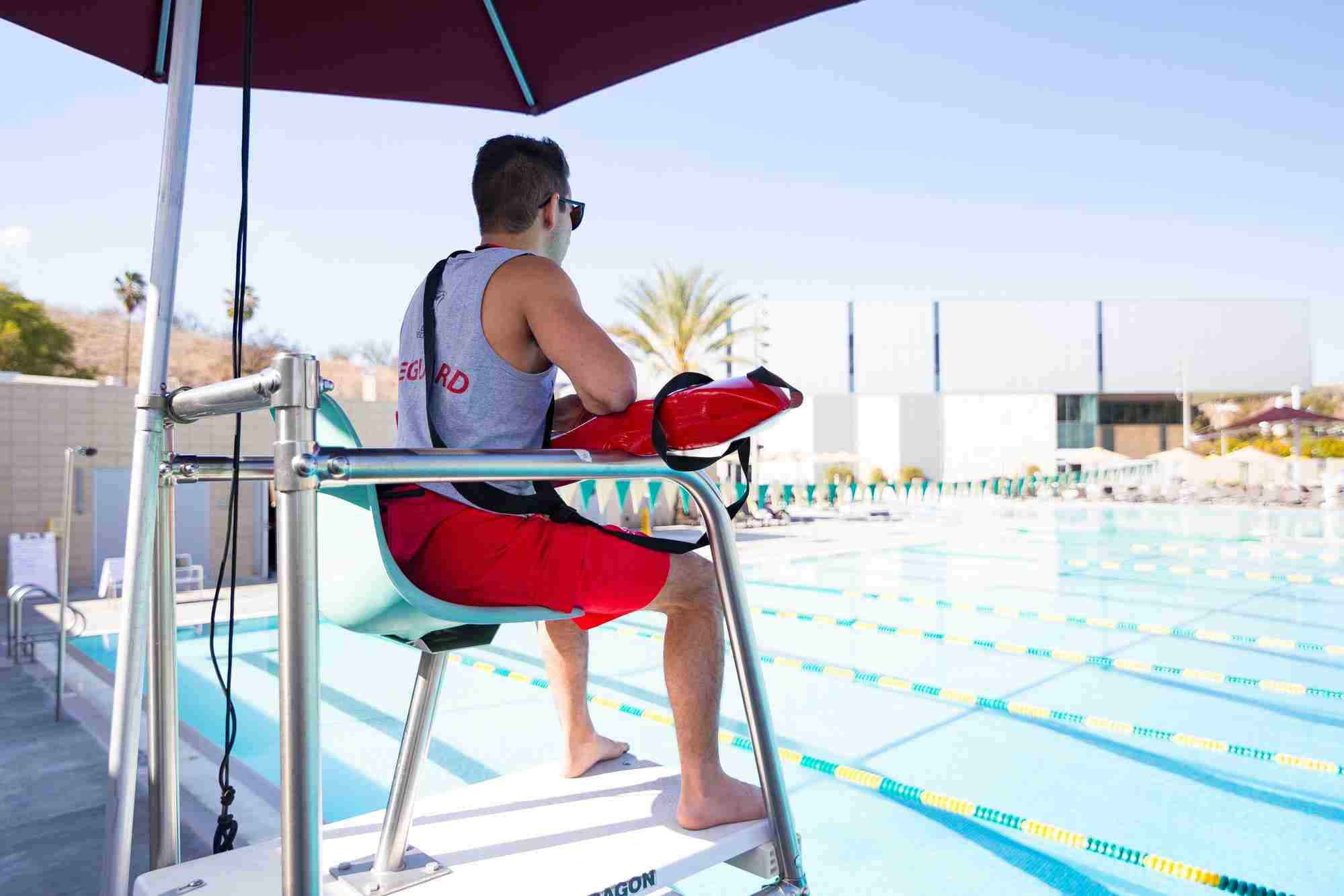 Lifeguard sitting on a watch tower at a pool