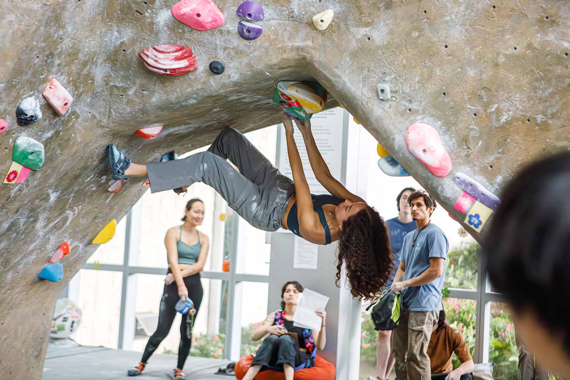 student is bouldering upside down on an indoor climbing wall
