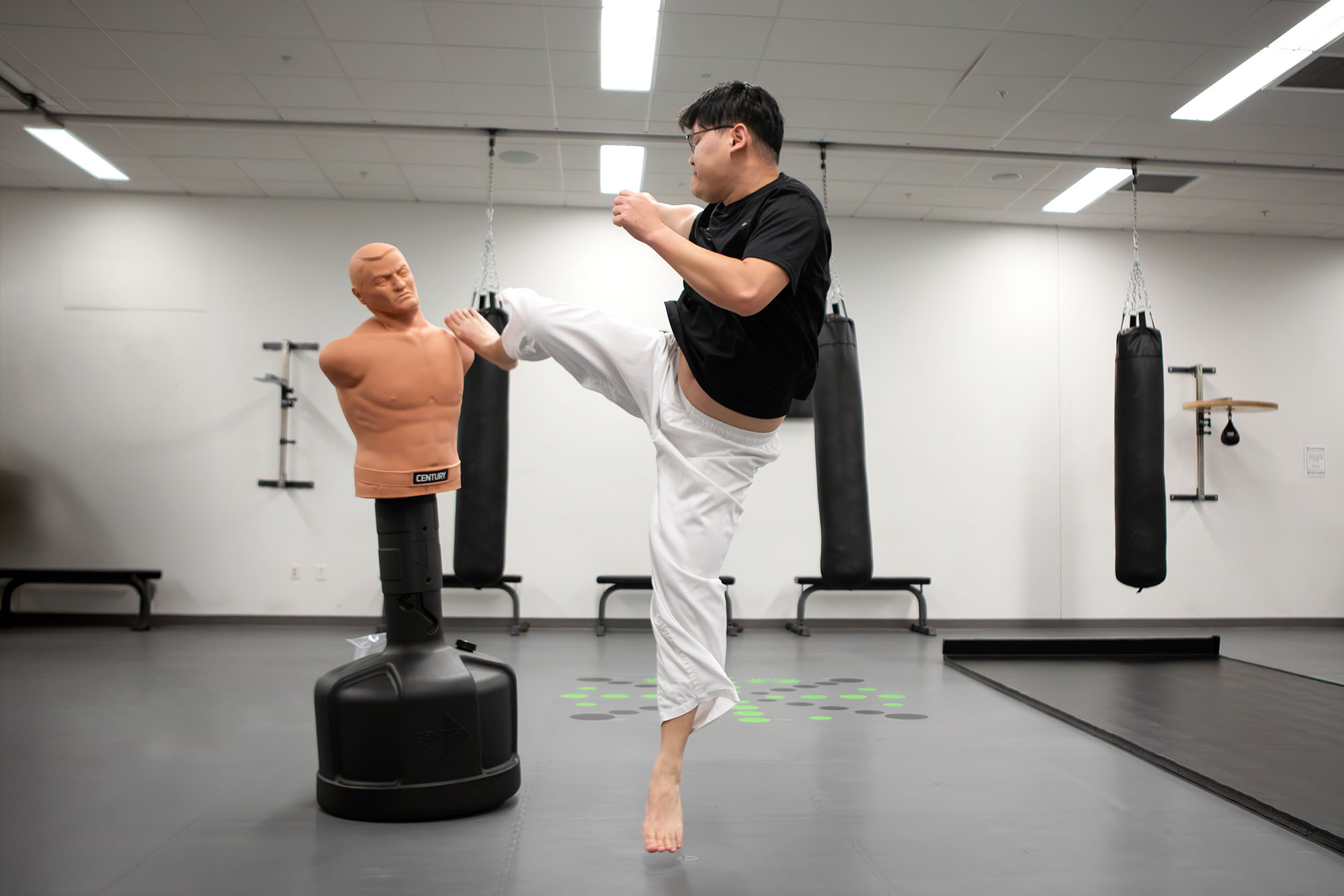 Student kicking a martial arts training dummy