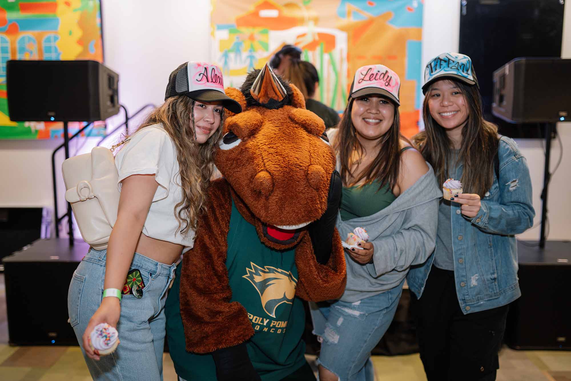 Three individuals are posing with a Billy Bronco mascot
