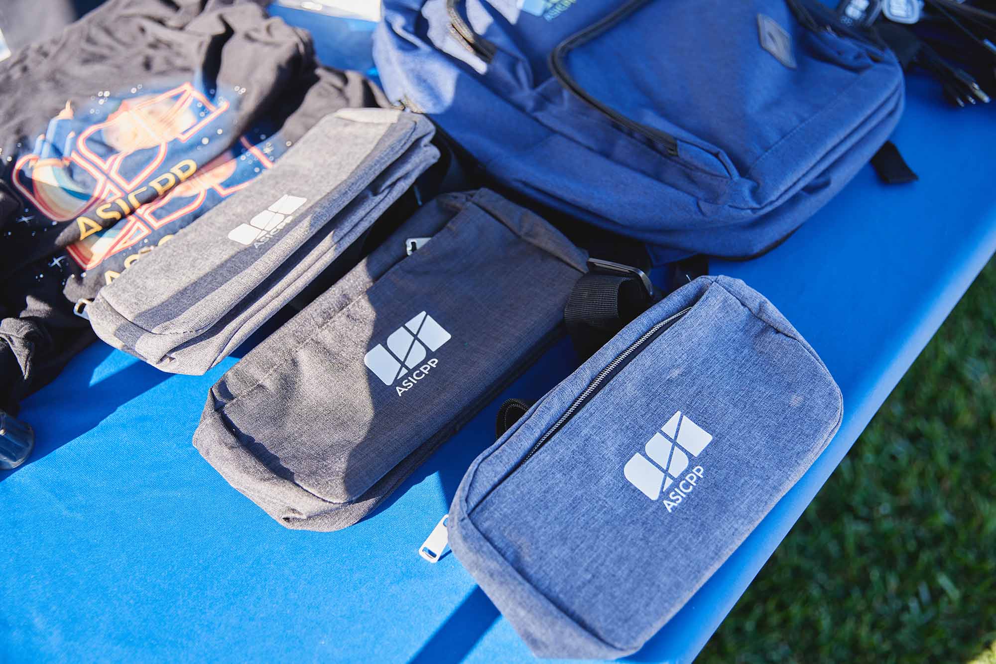 Various ASI merchandise bags on a blue table