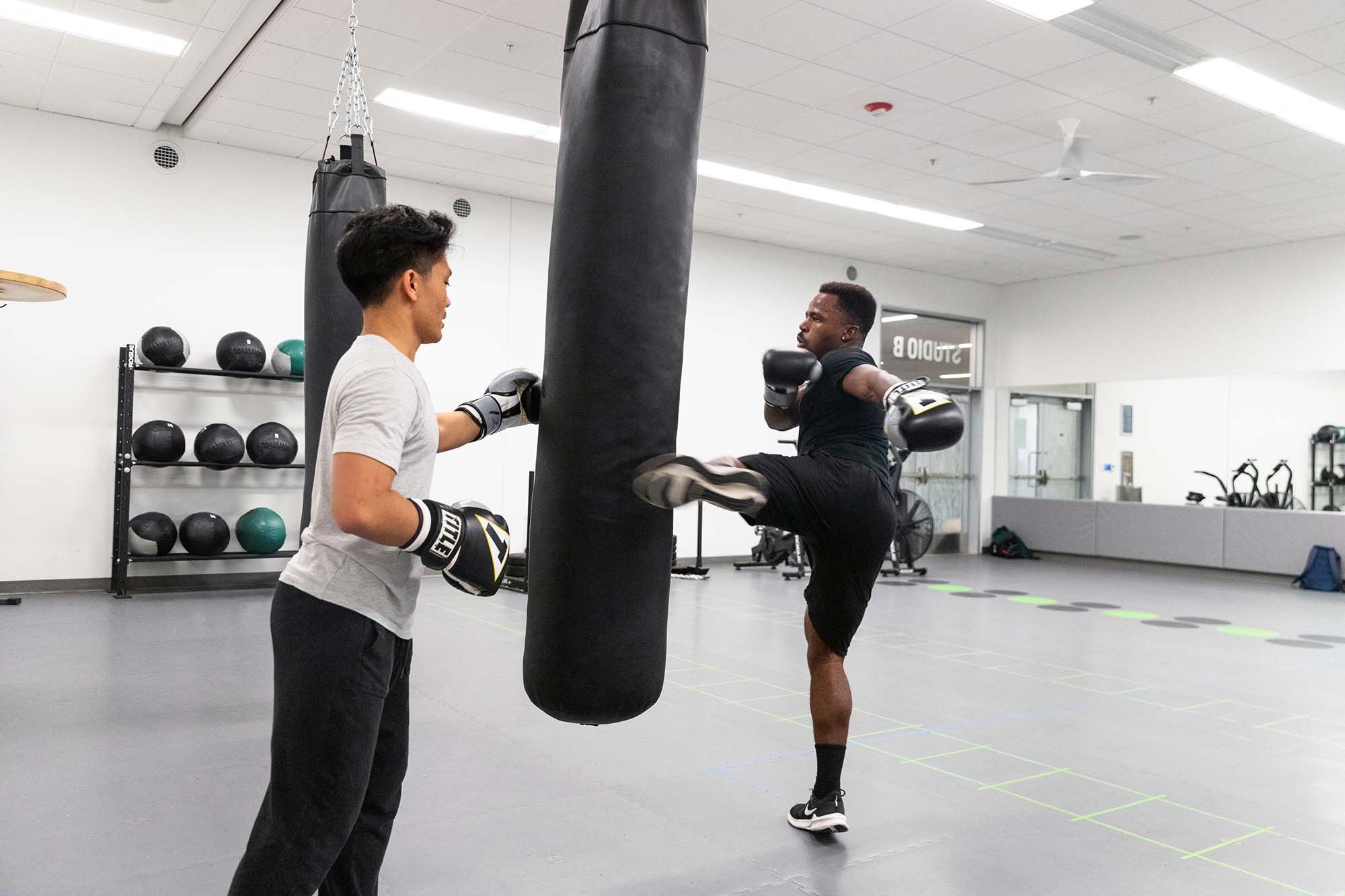two students practicing at a kick-boxing bag