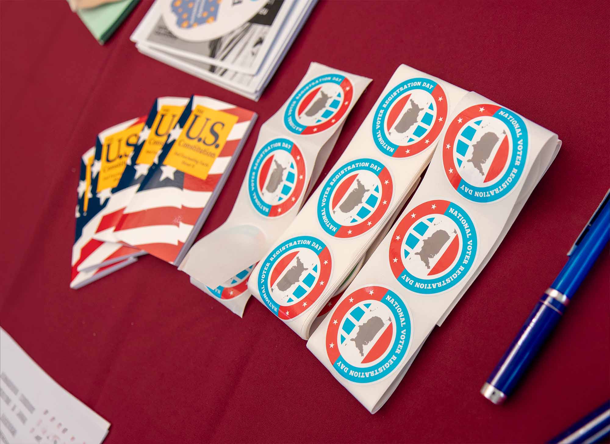Various elections pamphlets, stickers, papers, and pens on a table